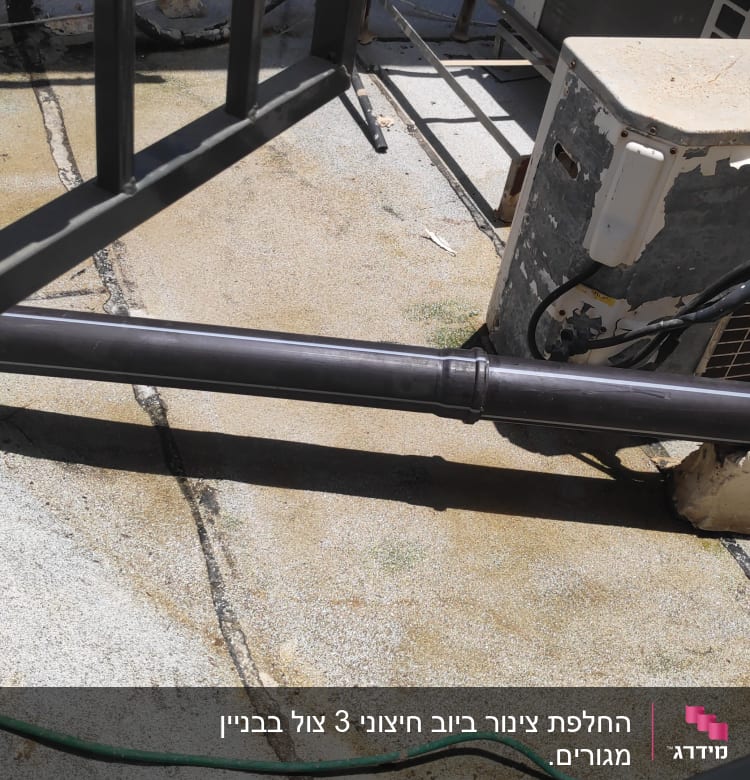 צינור פלסטיק שחור על גג עם מזגן ישן